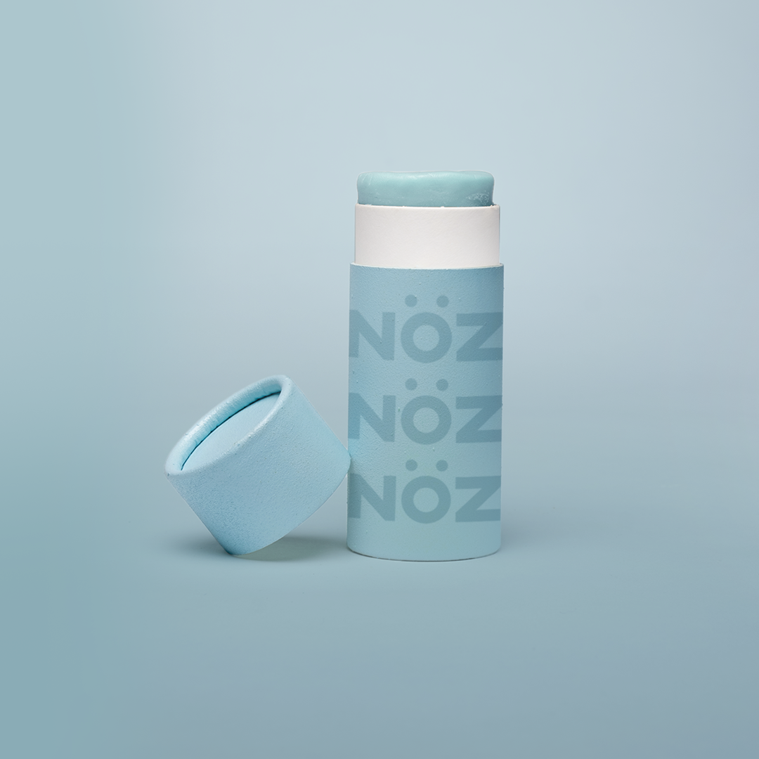 Light blue colored Nözscreen bottle with removed cap against light Blue gradient background.