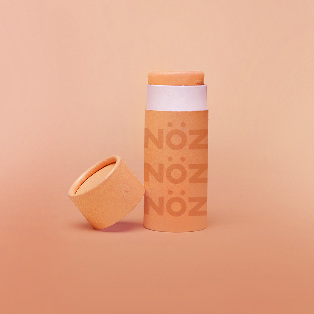 Orange colored Nözscreen bottle with removed cap against Orange gradient background.