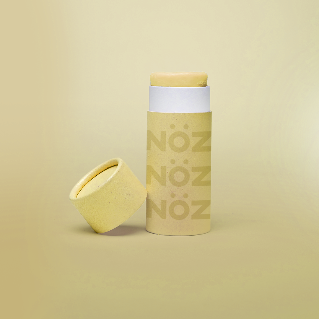 Pastel yellow colored Nözscreen bottle with removed cap against Yellow gradient background.